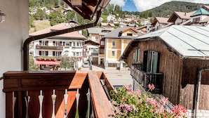 Un balcón de madera con vistas a un pueblo en la ladera.