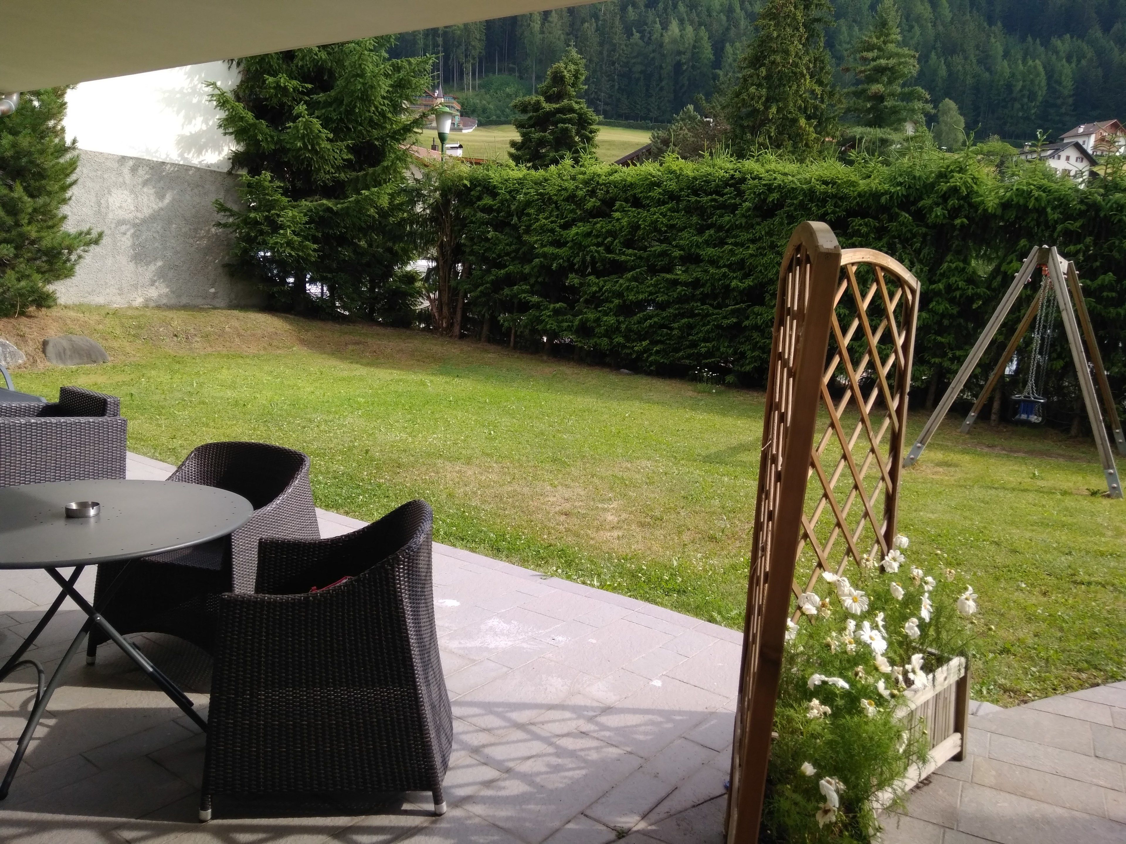 A patio with wicker furniture and a swing set.