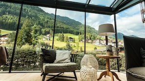 Una habitación moderna con ventanas amplias que ofrecen vistas a un valle verde y montañas.