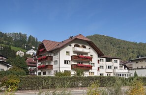 A multi-story hotel with balconies, surrounded by greenery and a mountainous backdrop. - Hotel Garni Villa Park (Ortisei)