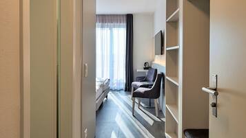 A hotel room with a bed, a desk, a chair, and a wardrobe.