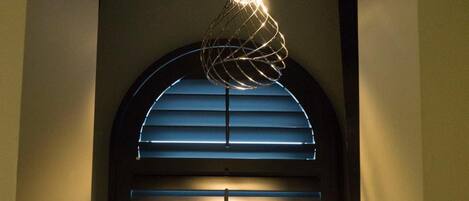 A cozy seating area with a bench, a decorative light fixture, and a window with blinds.