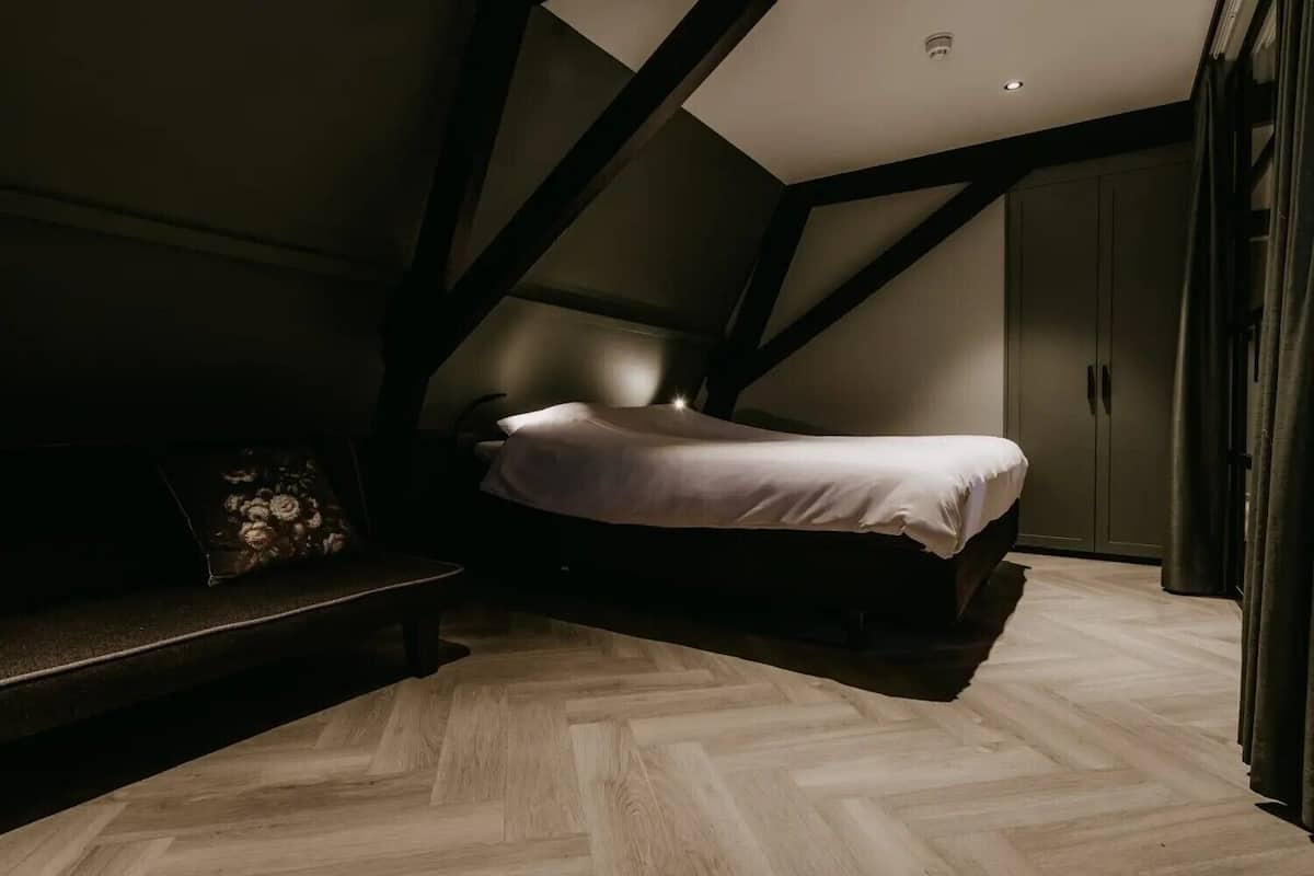 Un dormitorio con cama, un banco y un armario.