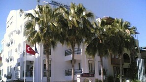 Un hôtel à la façade blanche, doté de nombreux balcons et bordé de palmiers.