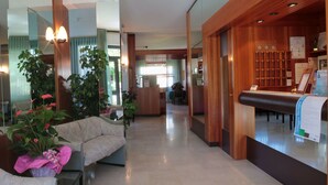 En hotellobby med en receptionsdisk, en sittgrupp och stora krukväxter.