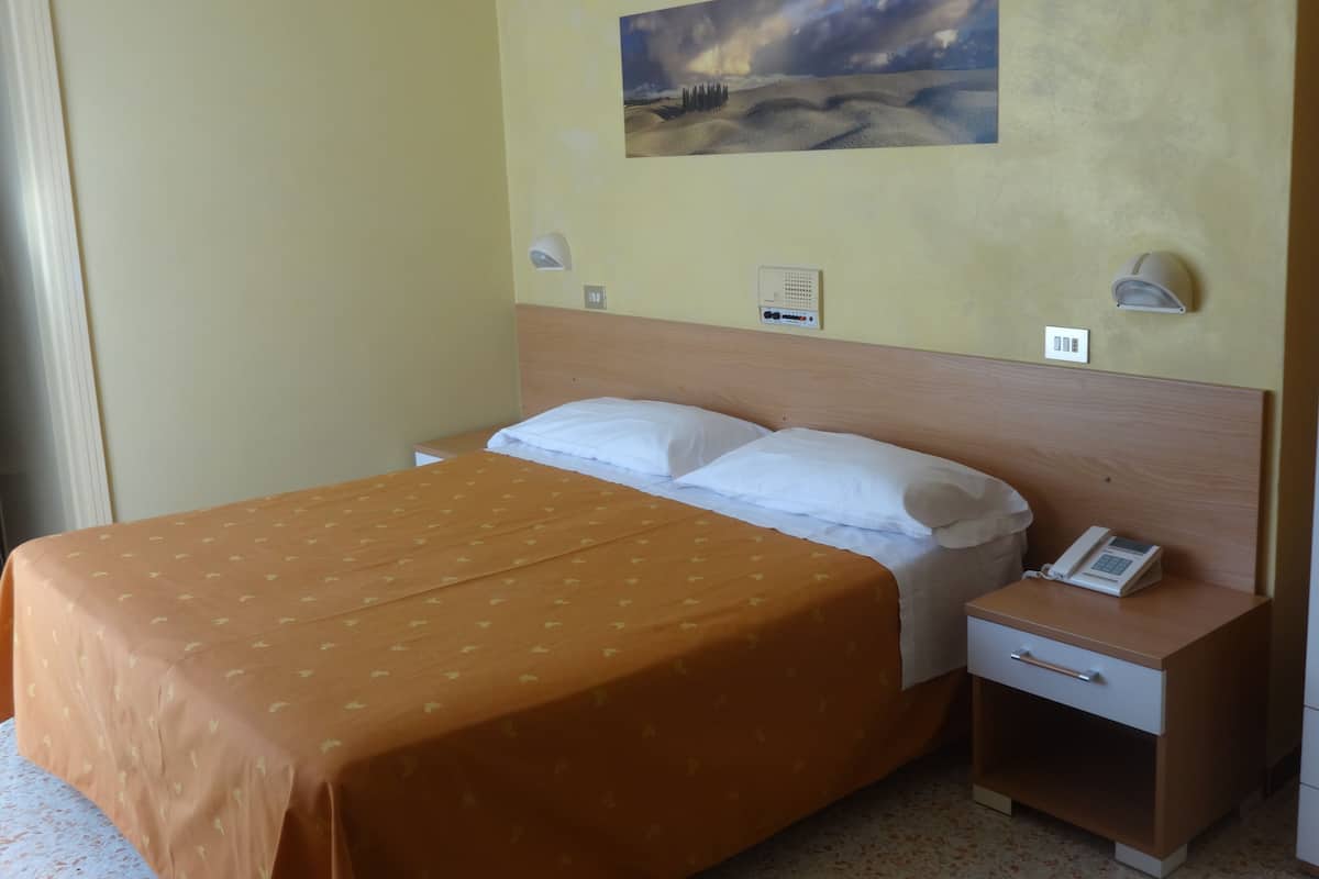 Une chambre d’hôtel avec un lit, une table de chevet avec un téléphone et un tableau au mur.