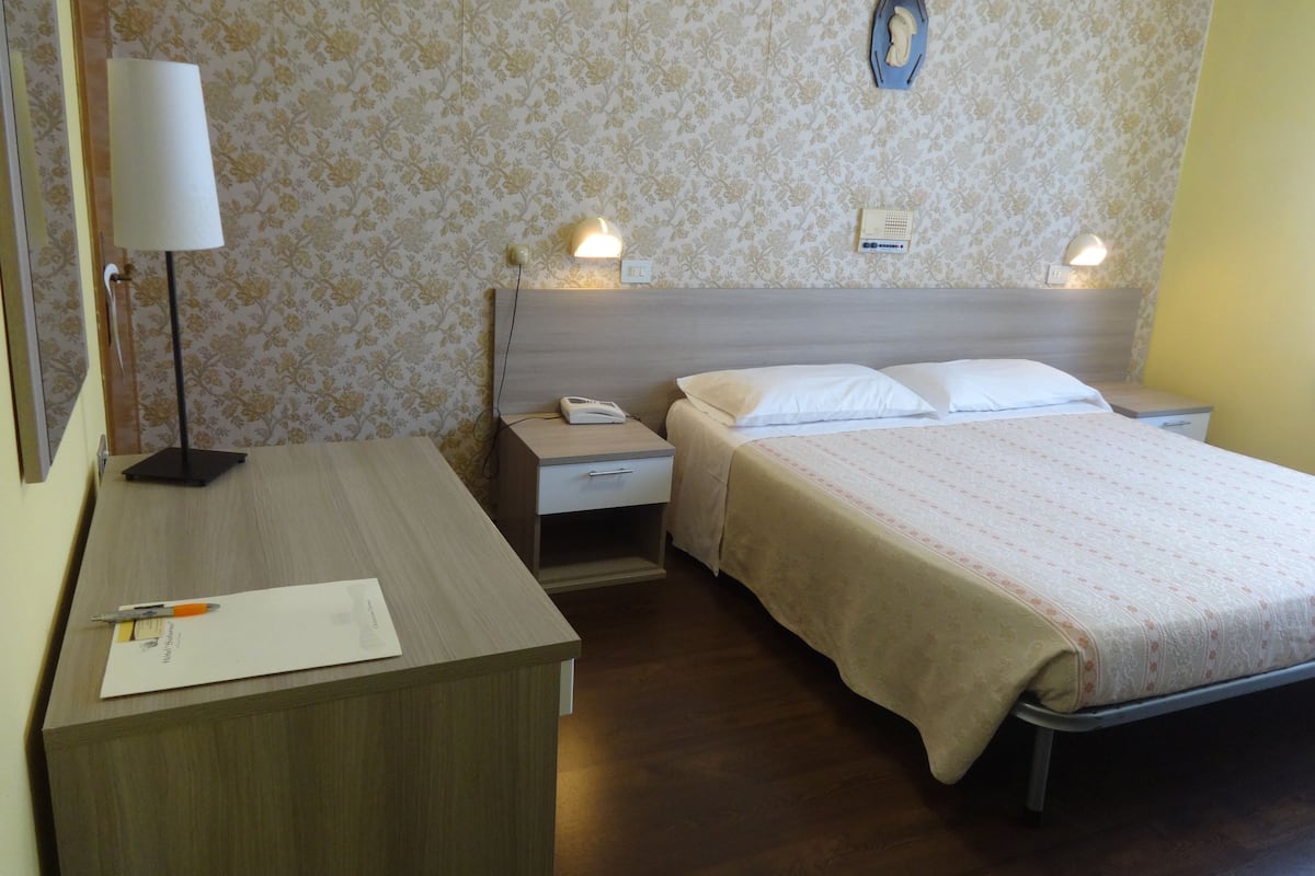 Une chambre d’hôtel équipée d’un lit, d’une table de chevet, d’une lampe et d’un téléphone fixé au mur.