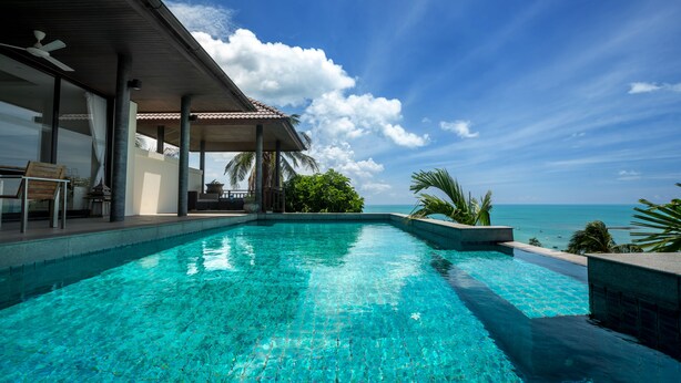 A clear blue pool with a view of the ocean, a covered seating area, and a palm tree. - Villa Baan Saitara (Koh Samui)