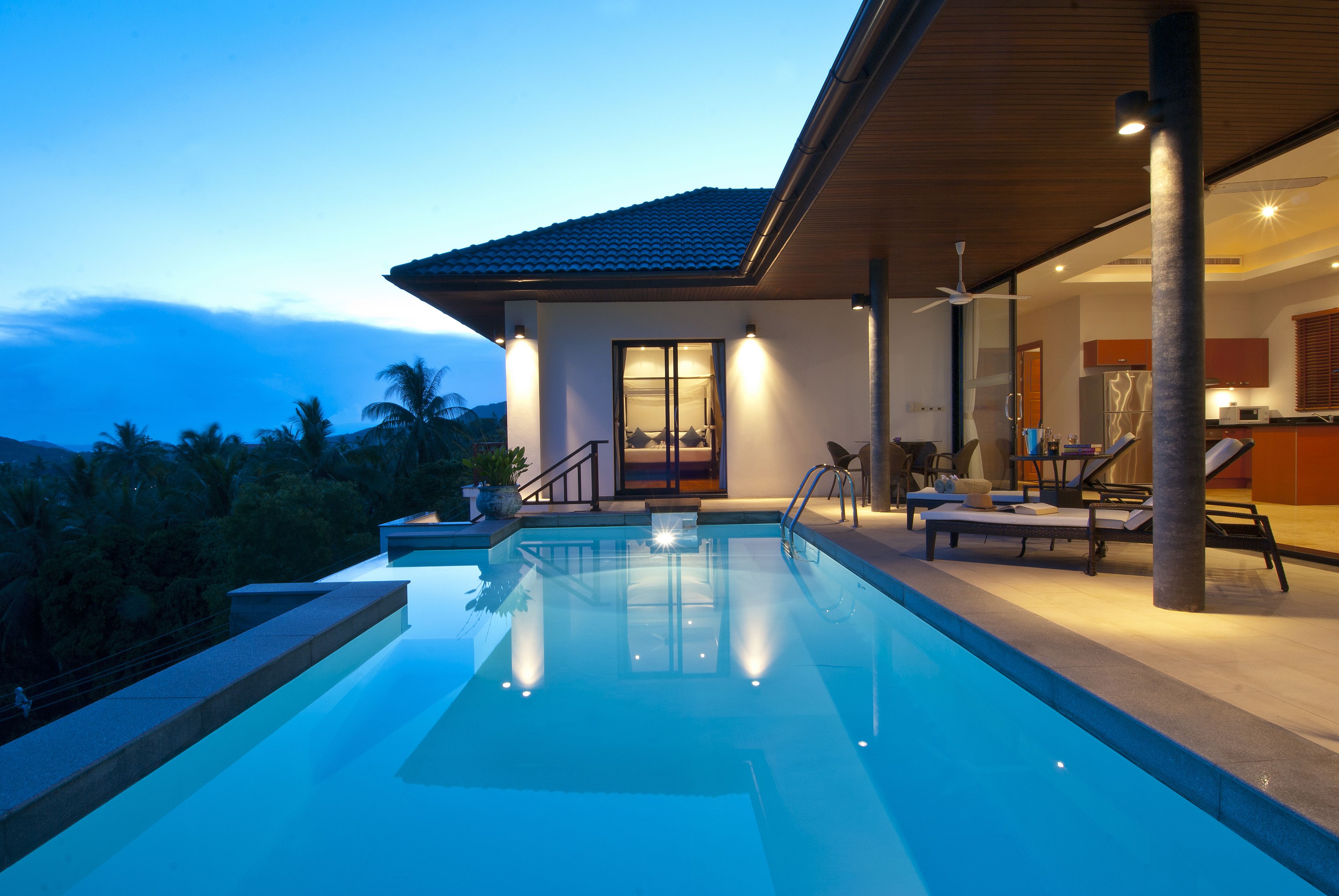 A modern house with a swimming pool, a covered patio, and a view of the mountains.
