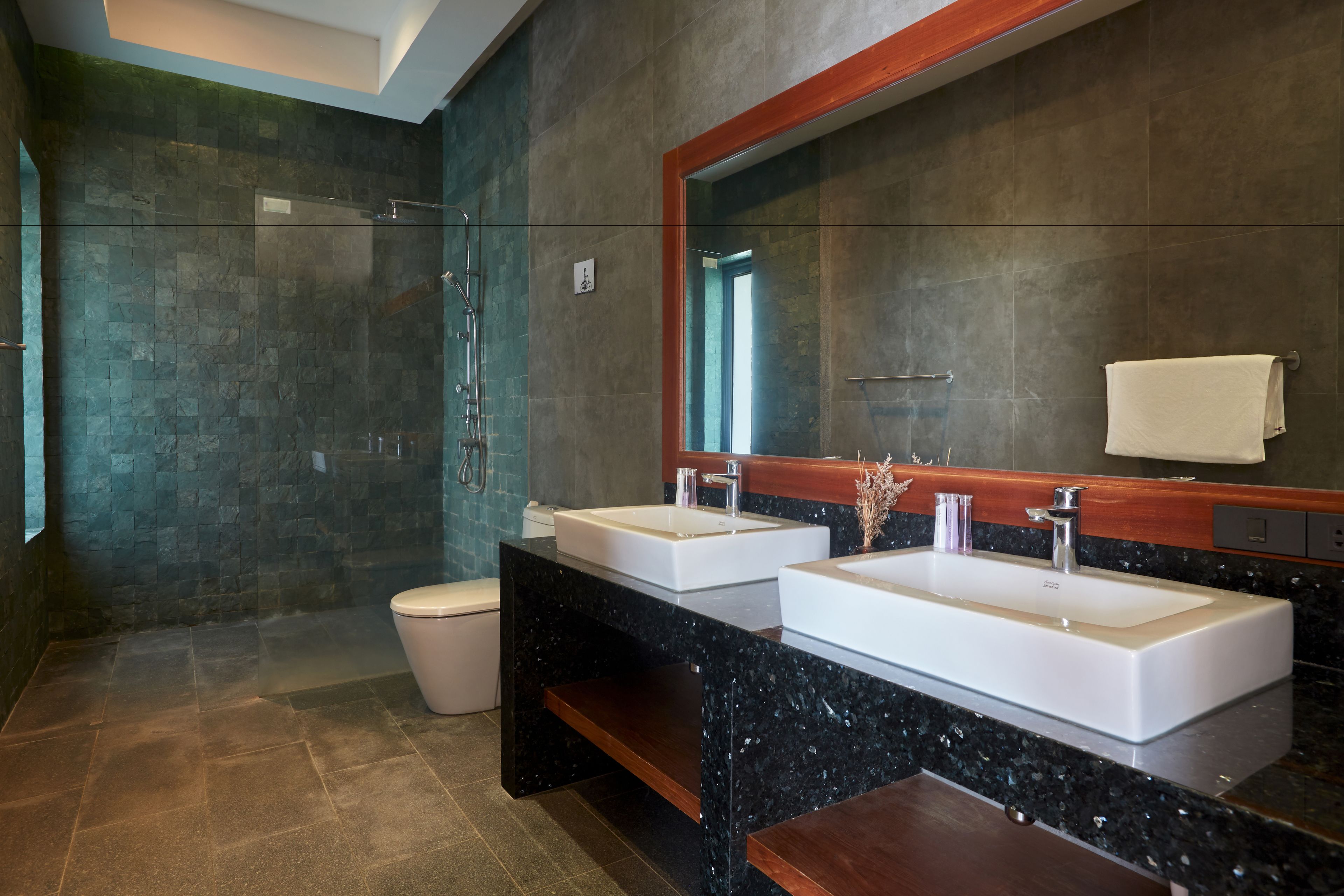 Un baño moderno con dos lavamanos, una cabina de ducha de vidrio y un espejo grande.