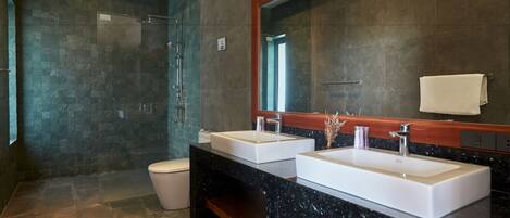 Un baño moderno con dos lavamanos, una cabina de ducha de vidrio y un espejo grande.