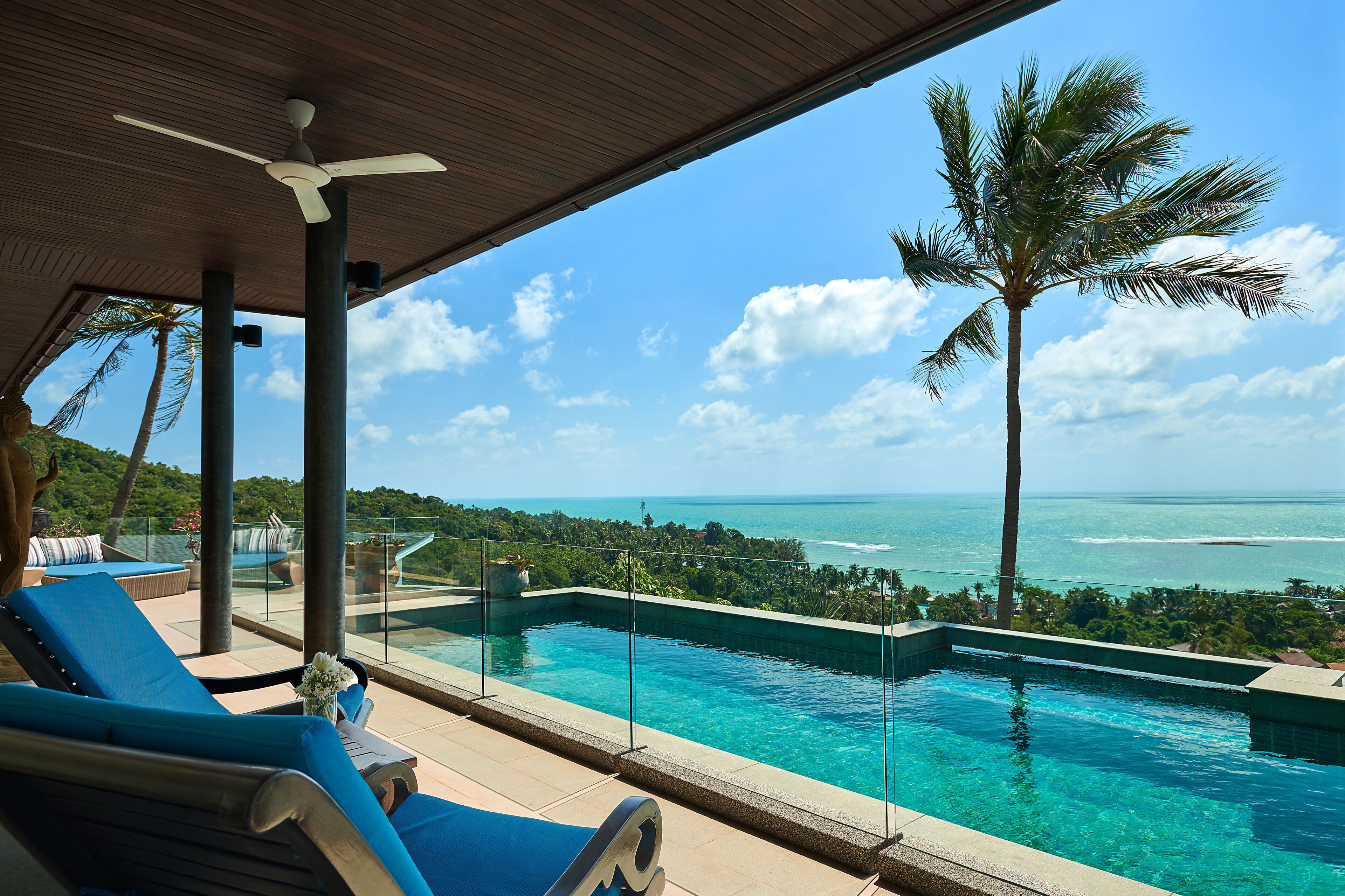 A pool with clear blue water, lounge chairs, and a view of the ocean.