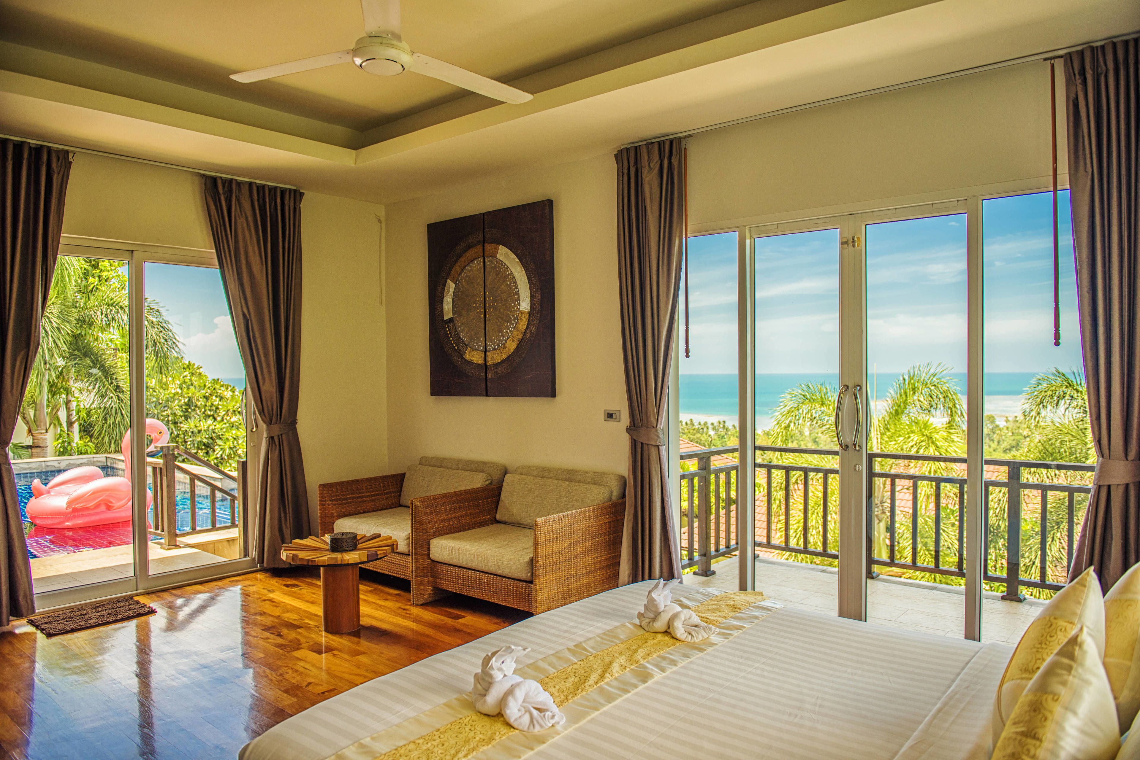 A hotel room with a bed, a sofa, a dining table, and a view of the ocean.