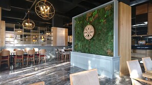 A modern interior with a bar area, seating, and a decorative wall with a clock. - Camlicesme Hotel (Bolu)