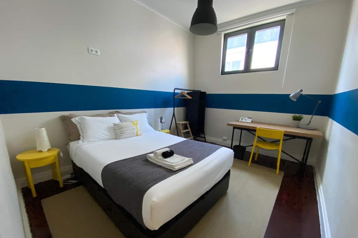 A neatly arranged bedroom with a bed, a desk, and a chair.