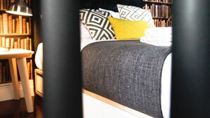 Een slaapkamer met een bed, een boekenkast en een bureau.
