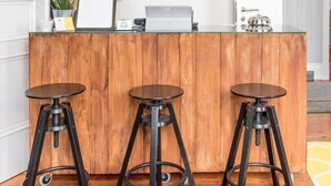 Een receptie met een houten balie, drie zwarte krukken en twee hanglampen.