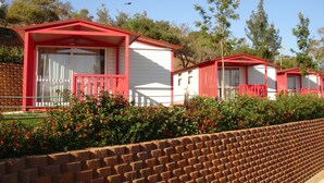 A row of red and white cabins with a brick wall in the foreground. - Parque de Campismo Orbitur Valverde (Lagos)