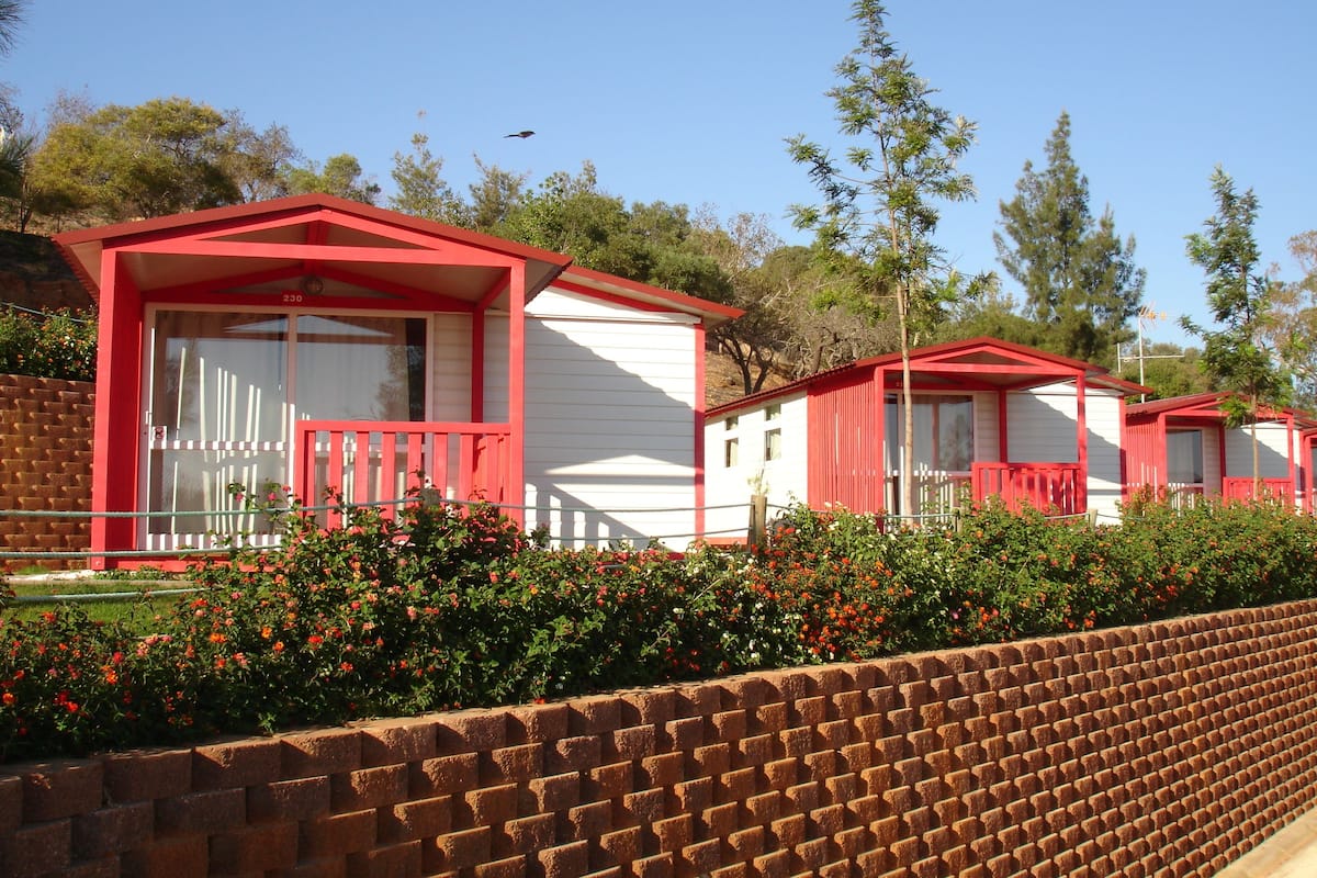 A row of red and white cabins with a brick wall in the foreground.