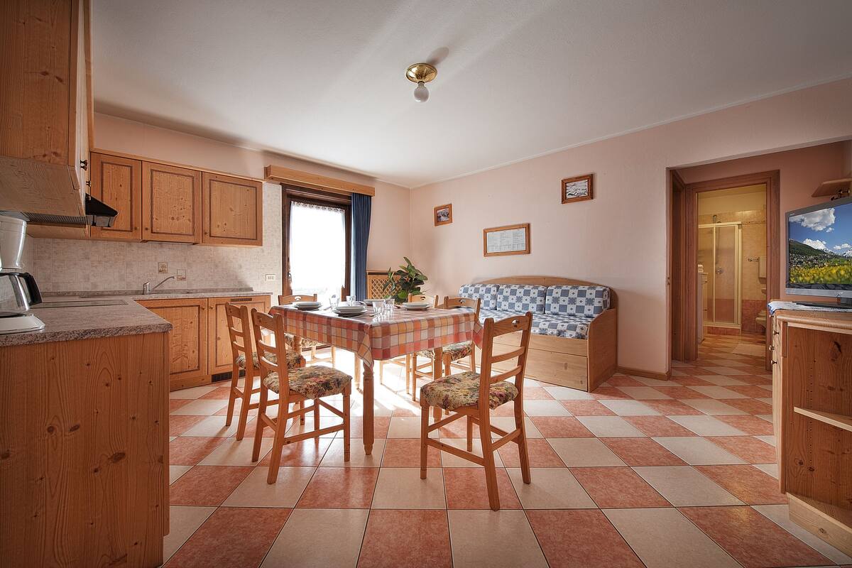 A kitchen with wooden cabinets, a dining table with chairs, and a checkered tablecloth.