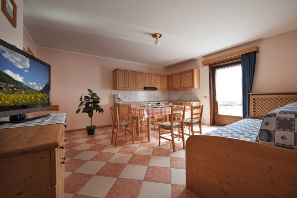 A compact room with a kitchen area, a dining table, and a bed. - Appartamenti Bait Carosello (Livigno)