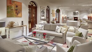 A spacious living room with a neutral color palette, featuring a glass coffee table, sofas, and armchairs. - Das Alpenhaus Gasteinertal (Bad Hofgastein)