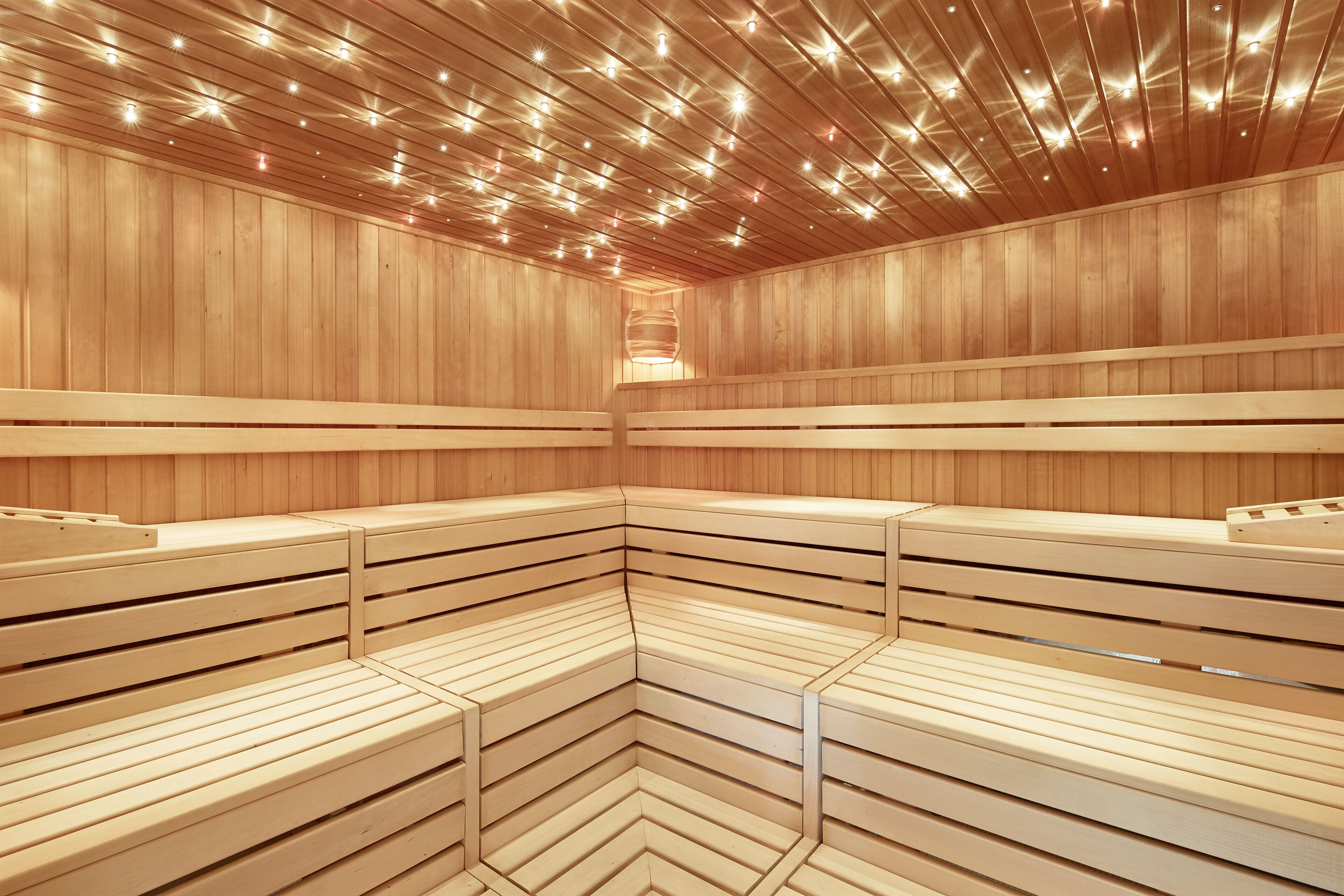 Un sauna avec des bancs en bois et un plafond doté d’un éclairage encastré.