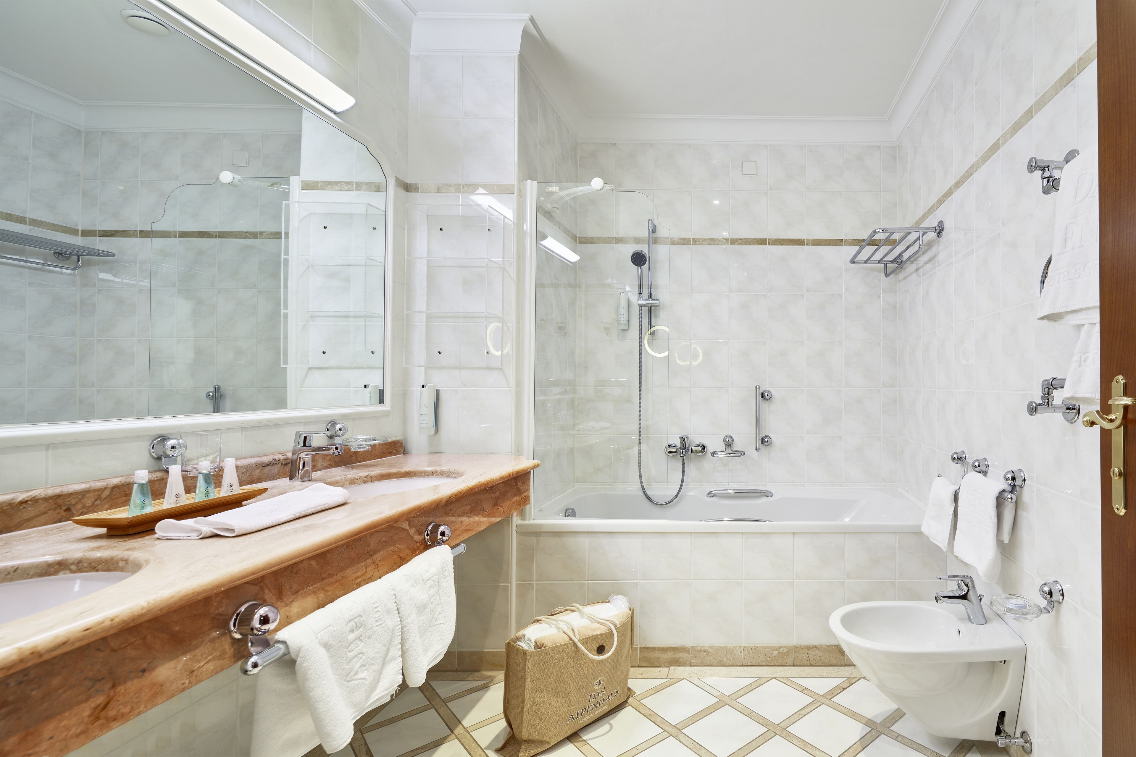 Ein modernes Badezimmer mit Marmorplatte, einem großen Spiegel, einer Badewanne, einer Dusche und einem Waschbecken.