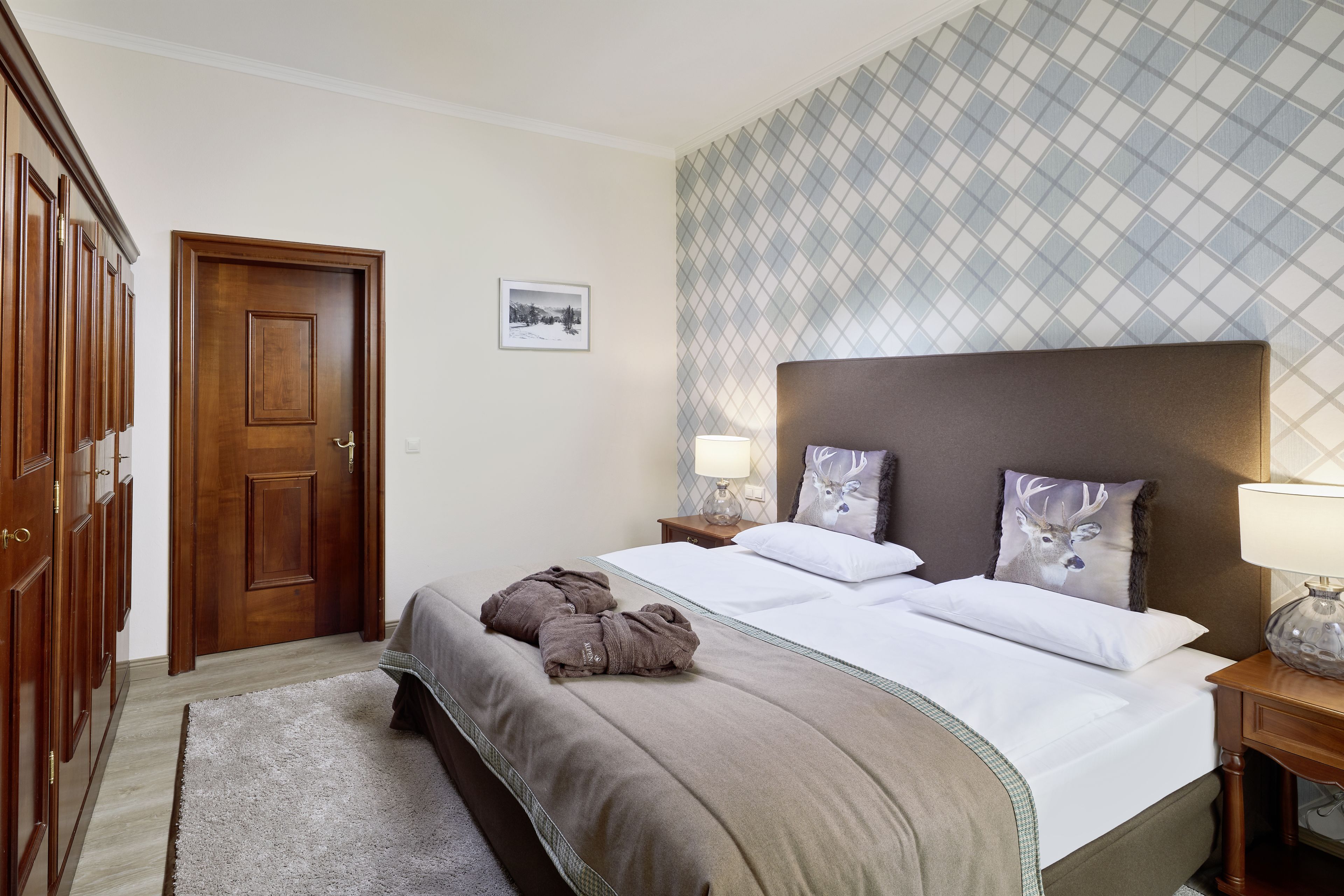 Habitación de hotel con una cama grande, un armario de madera y un papel tapiz estampado.