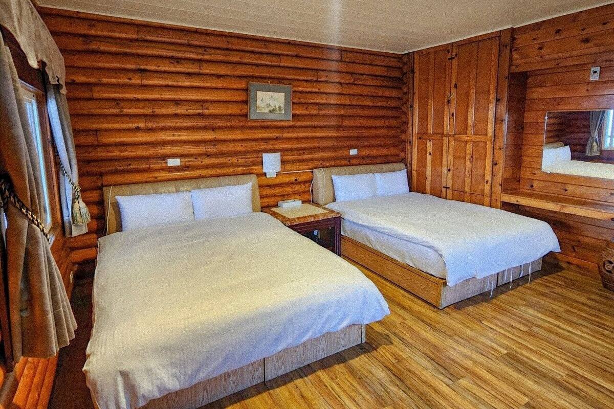 A wooden cabin-style room with two beds, wooden walls, and a small window.