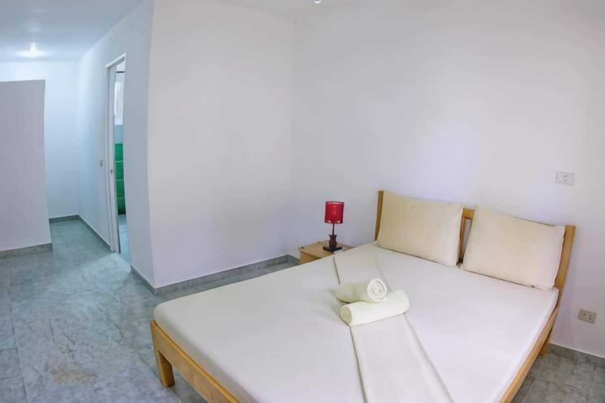 A bedroom with a bed, a nightstand, and a red lamp.