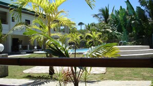 A courtyard with a pool, palm trees, and a building with a tiled roof. - Alona Swiss Resort (Panglao)