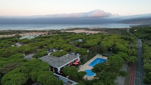 Vista aérea de un resort con piscina, abundante vegetación y una playa.