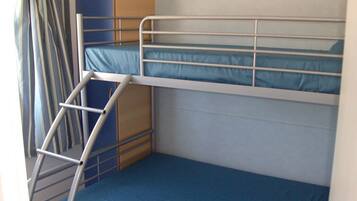 A bunk bed room with a ladder, a blue mattress, and a wooden cabinet.