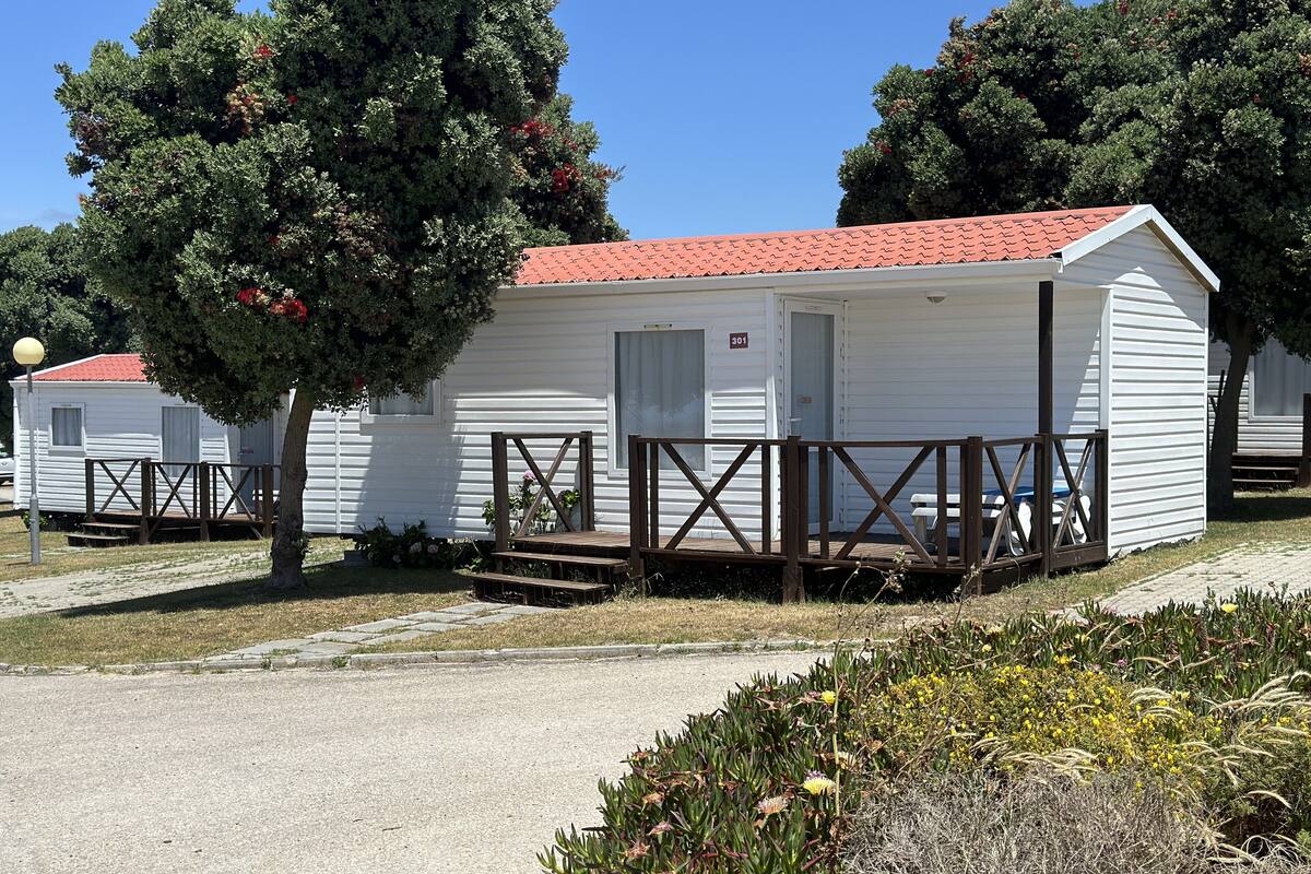 A row of mobile homes with a red-tiled roof, wooden decks, and a paved driveway.