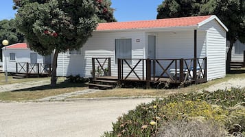 Une rangée de maisons mobiles avec un toit recouvert de tuiles rouges, des terrasses en bois et une allée pavée.