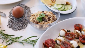 Ein Frühstückstisch mit verschiedenen Speisen, darunter Eier, Toast und eine Schüssel Tomaten.
