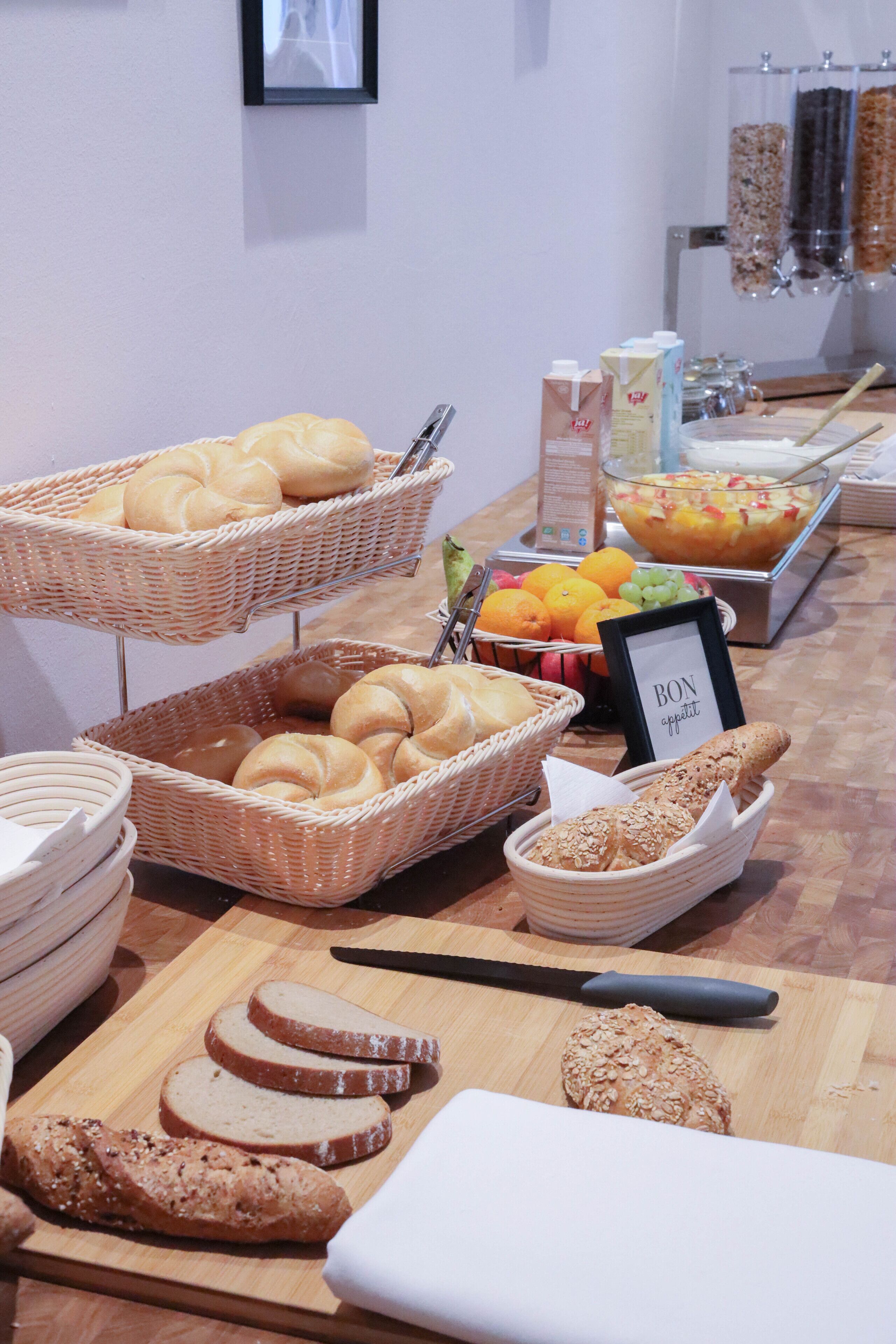 Una mesa de buffet con panes, frutas y bebidas variadas.