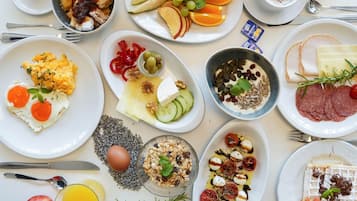 Variedad de platillos de desayuno, como huevos, frutas, queso y carnes.