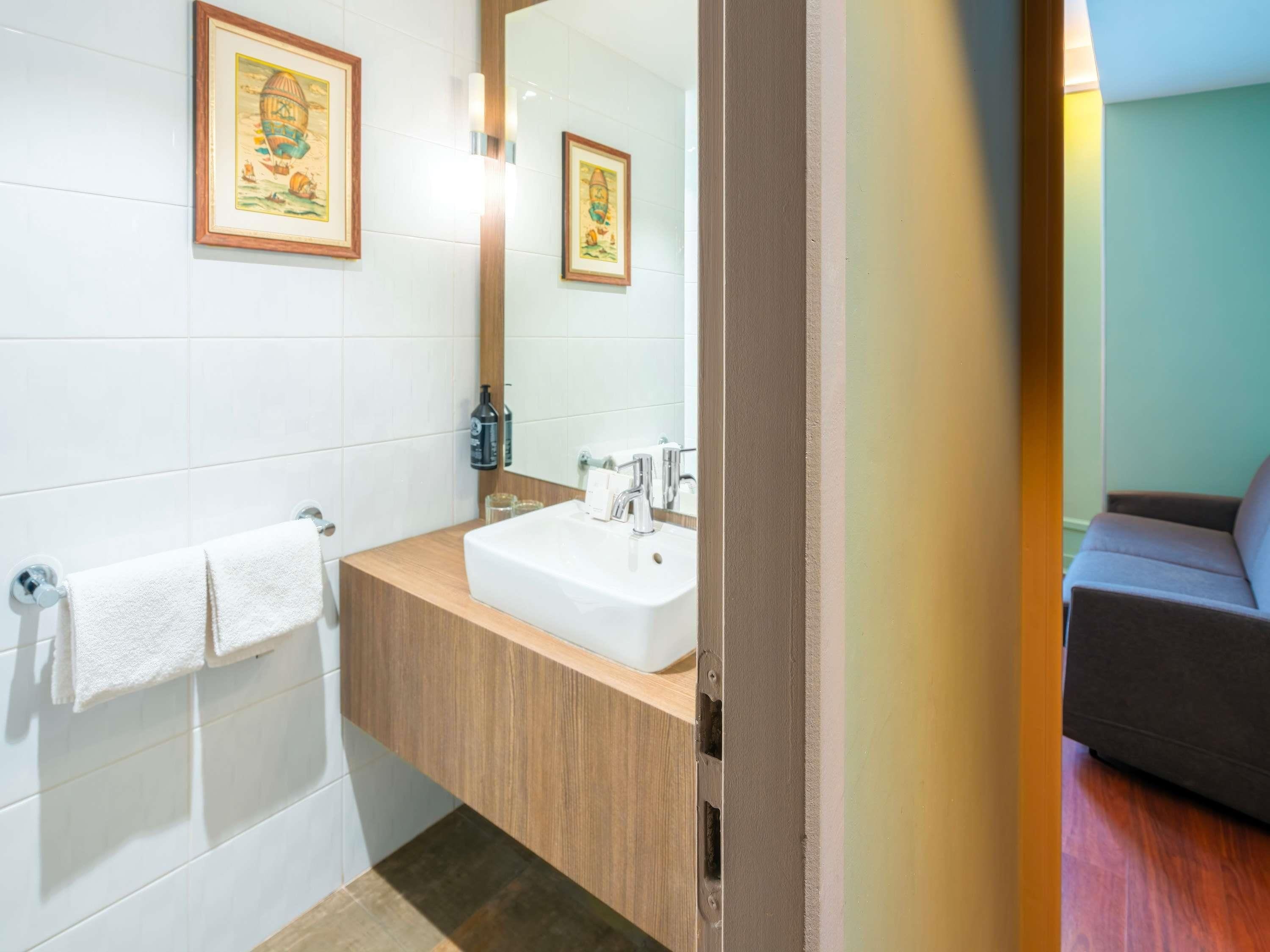 Un baño con lavabo, espejo y toallero.