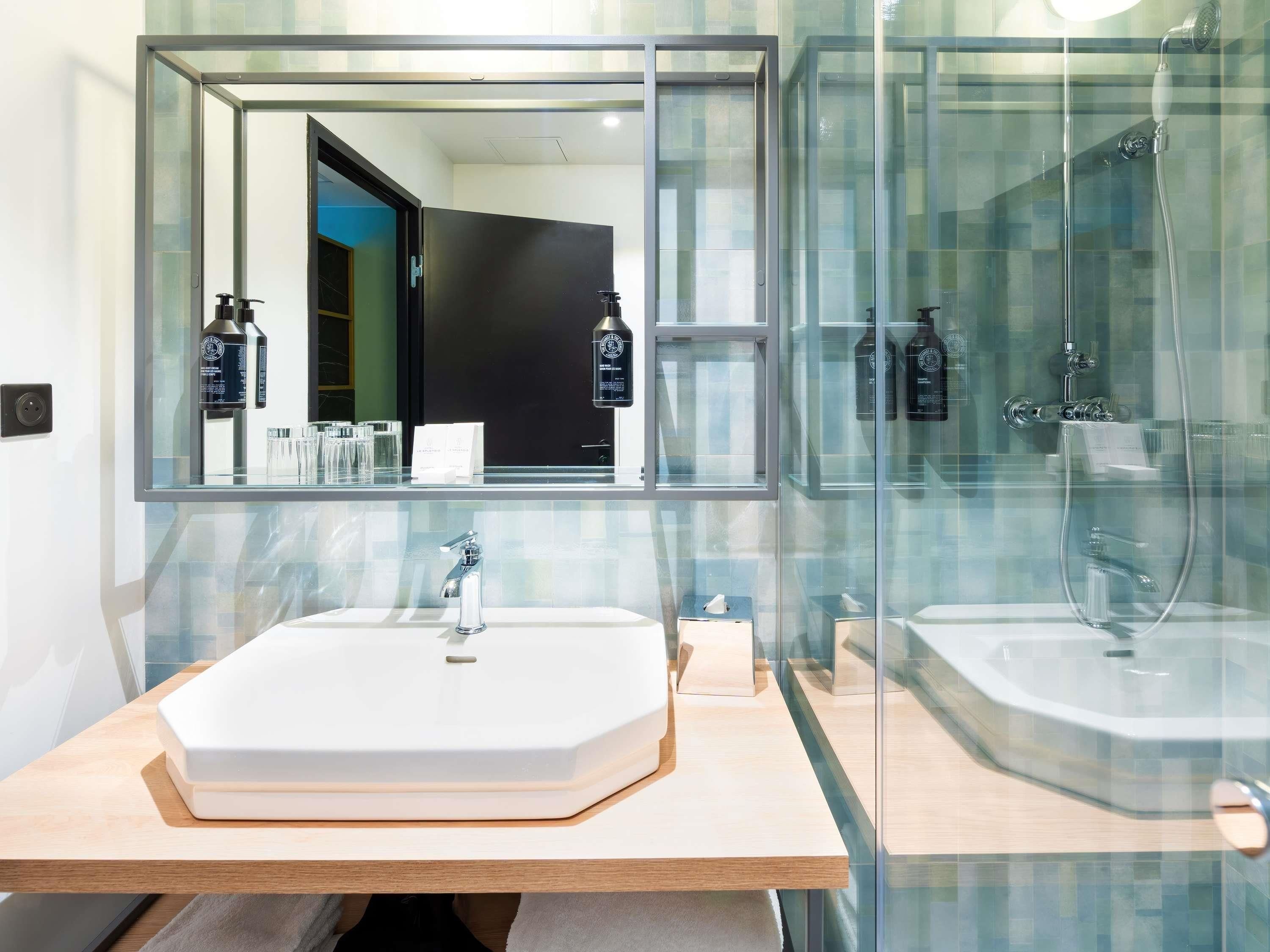 Un baño moderno con un espejo grande, un lavabo blanco y una ducha con cerramiento de vidrio.