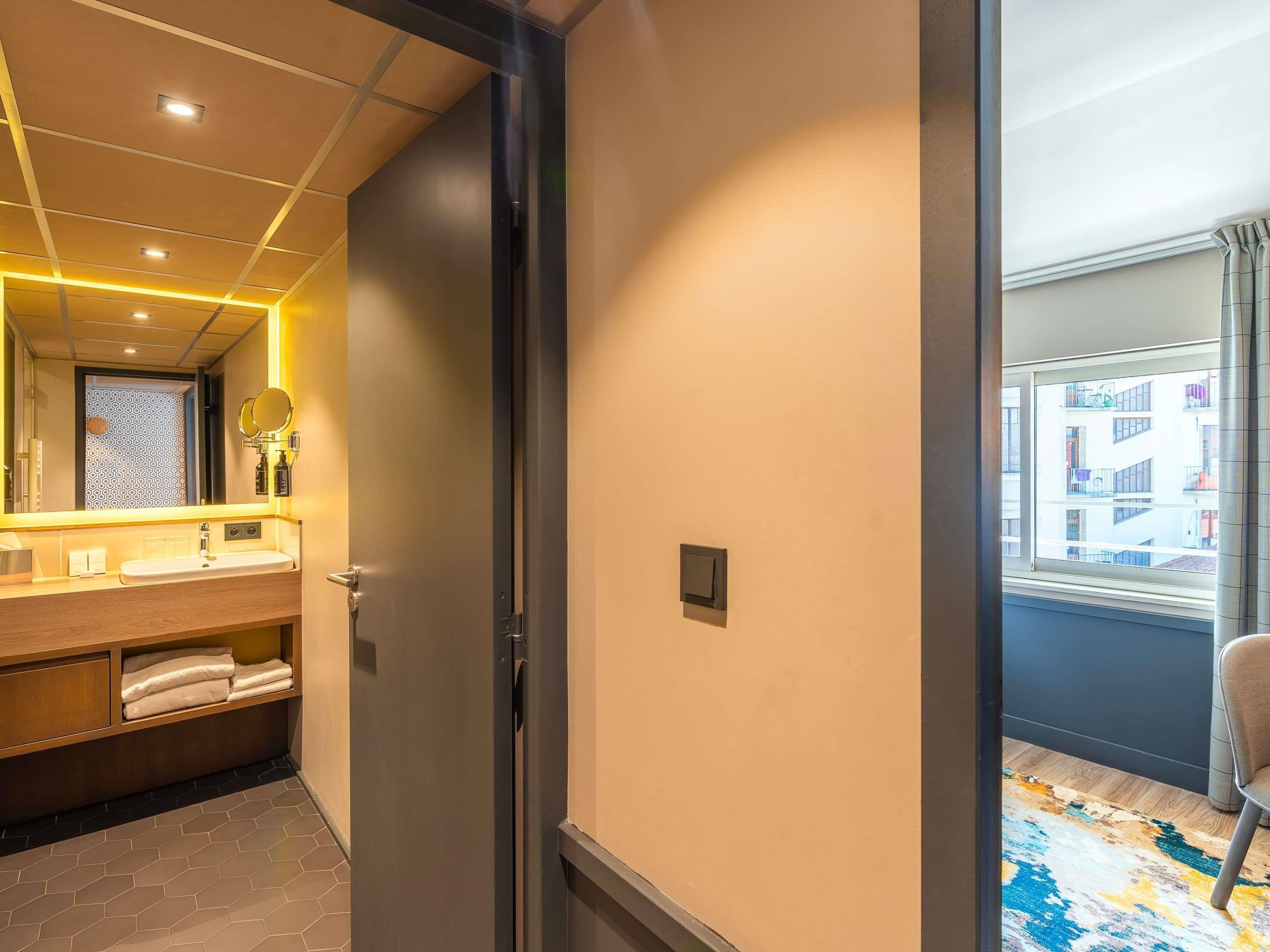 A modern bathroom with a large mirror, a sink, and a towel rack.