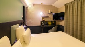 A hotel room with a large bed, a desk with a flat-screen TV, a coffee machine, and a shelf with decorative items. - Splendid Hotel Lac d'Annecy - Handwritten Collection (Annecy)