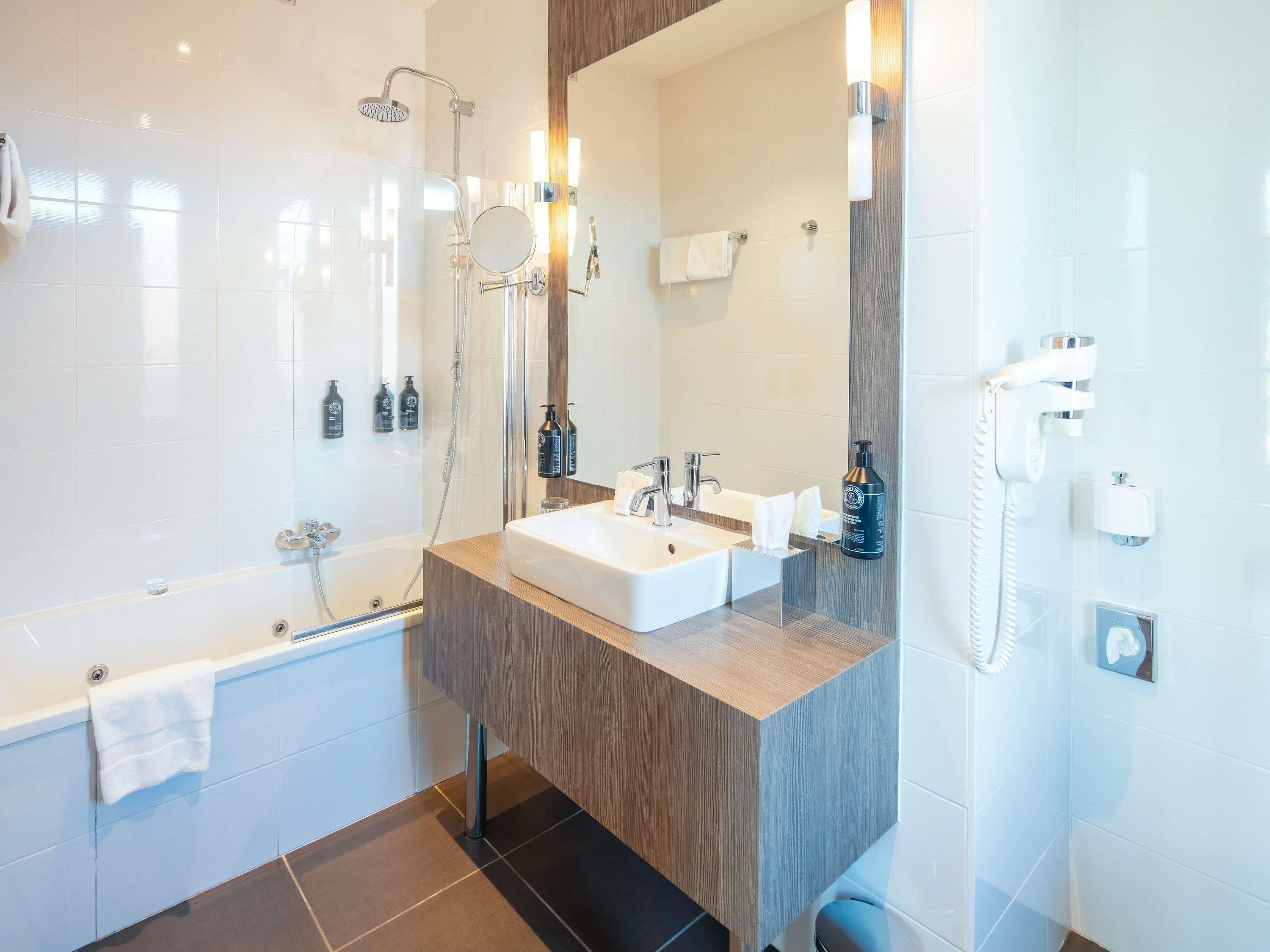 Ein modernes Badezimmer mit Badewanne, Dusche, Waschbecken und Spiegel.