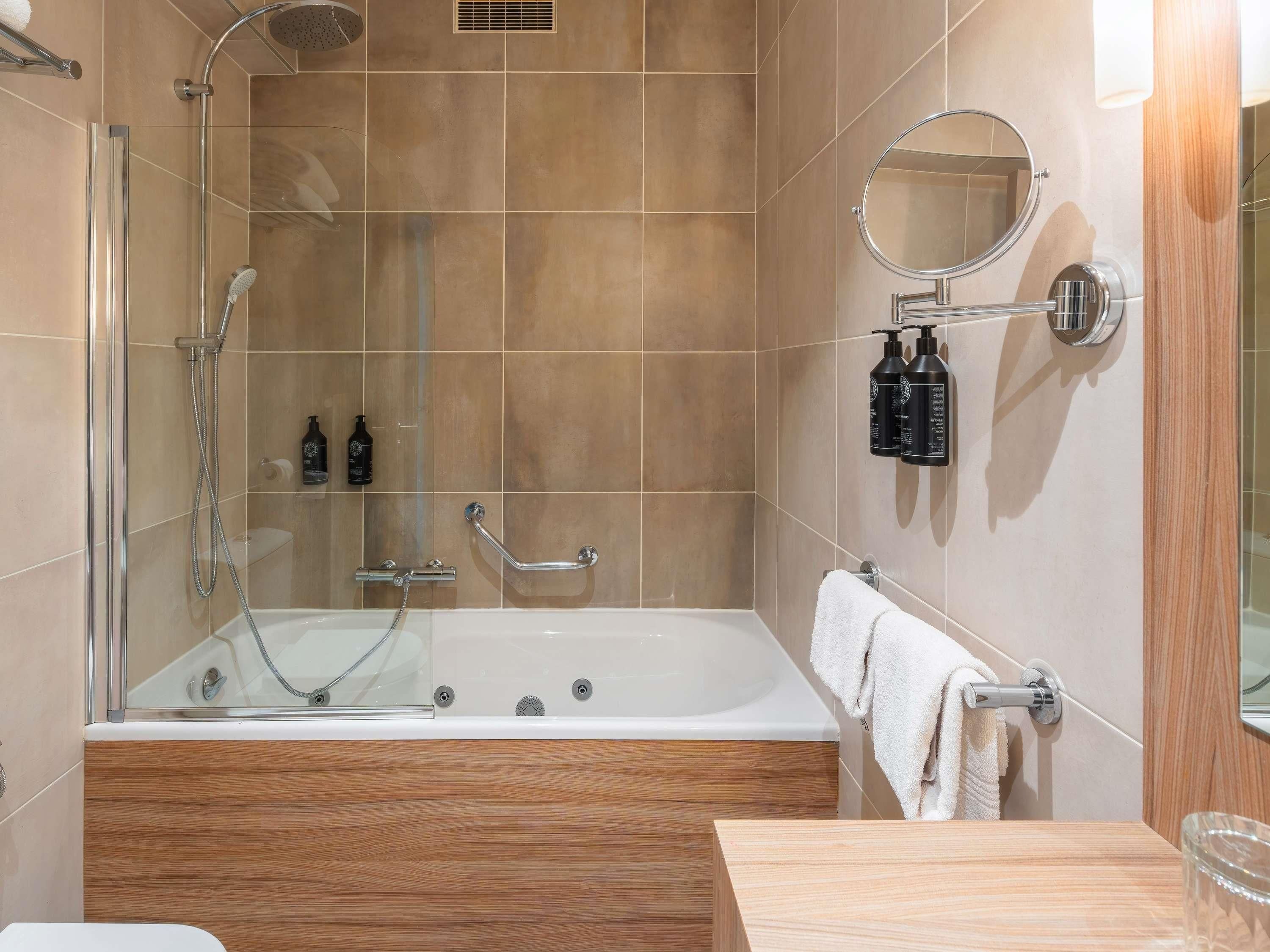 Un baño moderno con ducha envuelta en vidrio, una bañera independiente y un tocador de madera.