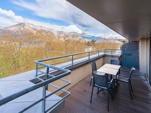 An outdoor balcony with a table and chairs, a metal railing, and a view of mountains. - Splendid Hotel Lac d'Annecy - Handwritten Collection (Annecy)