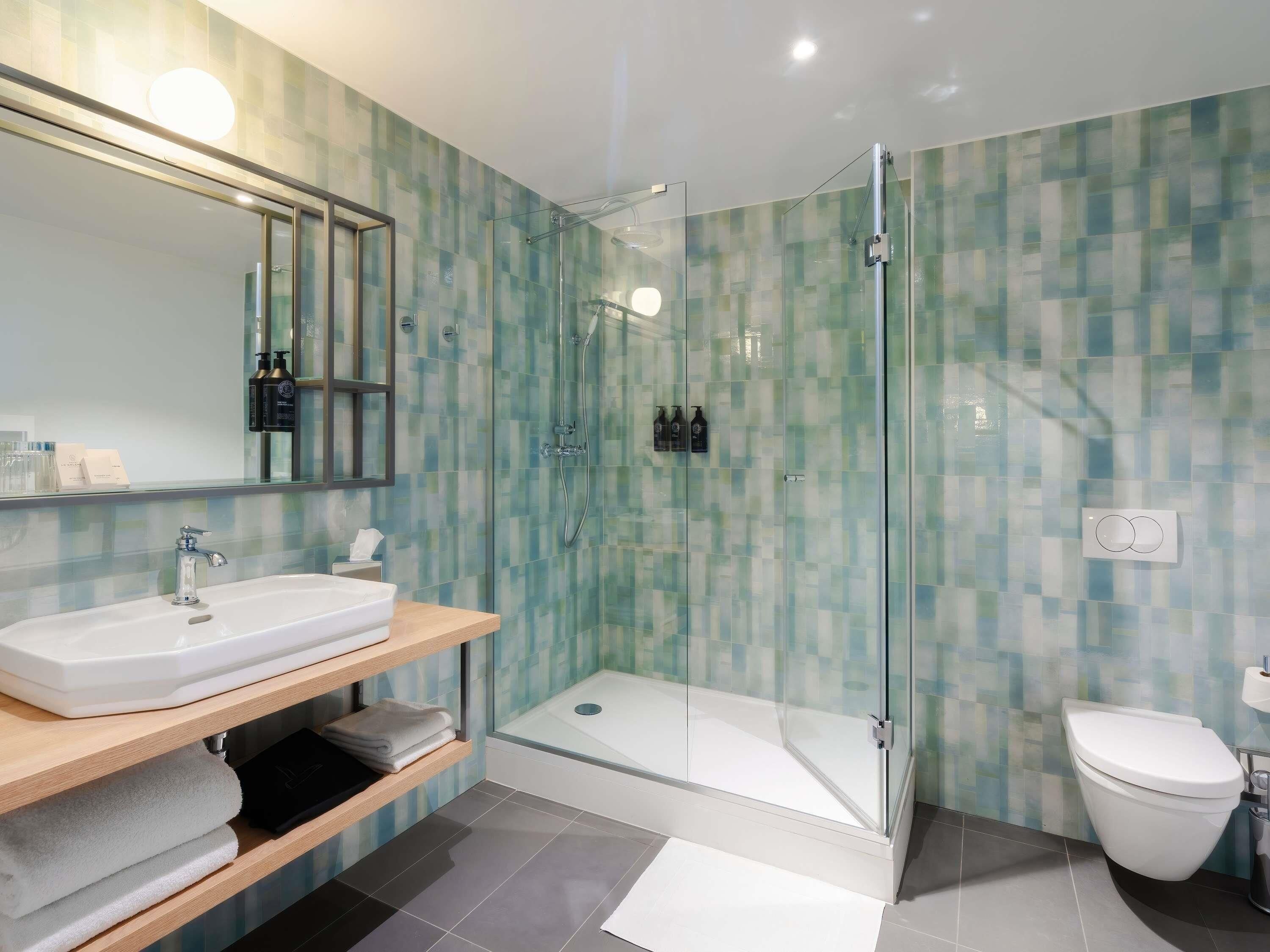 A modern bathroom with a glass-enclosed shower, a white sink, and a toilet.