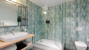 A modern bathroom with a glass-enclosed shower, a white sink, and a toilet.