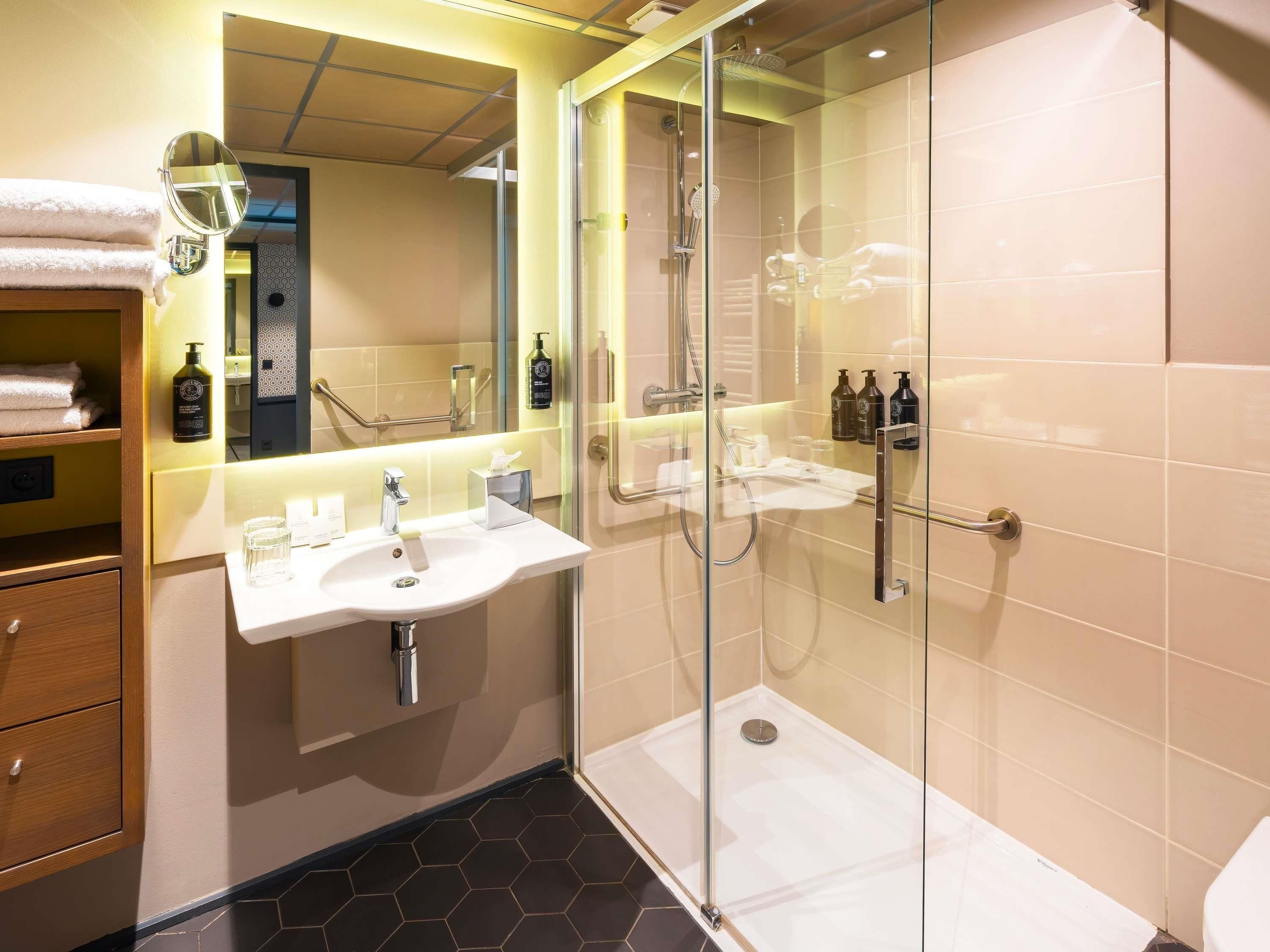 Een moderne badkamer met een douchecabine van glas, een wastafel met spiegel en een wasbak.