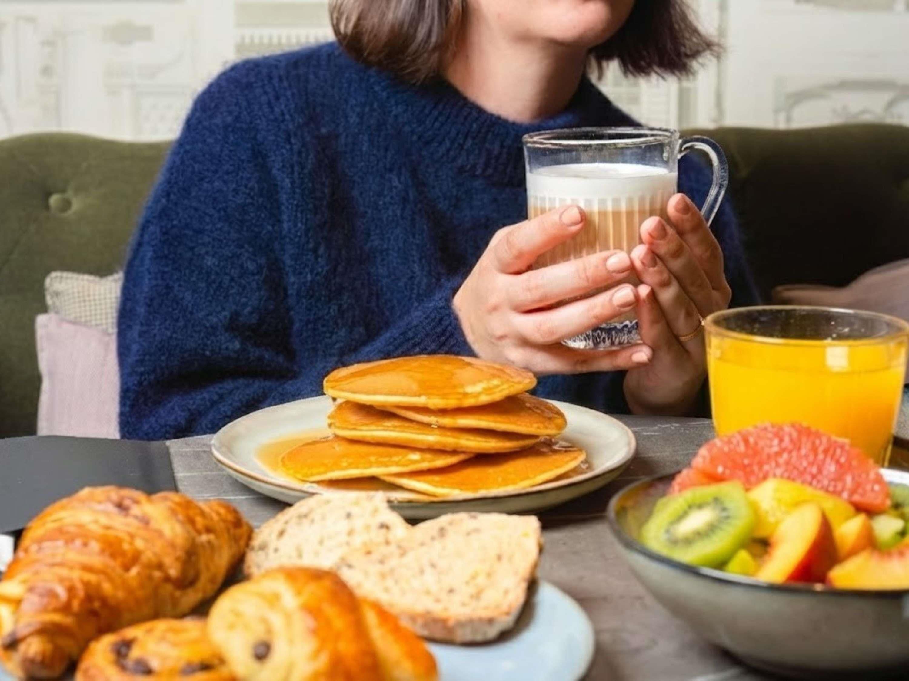 Ein Frühstückstisch mit Pfannkuchen, Croissants und einer Obstschale.